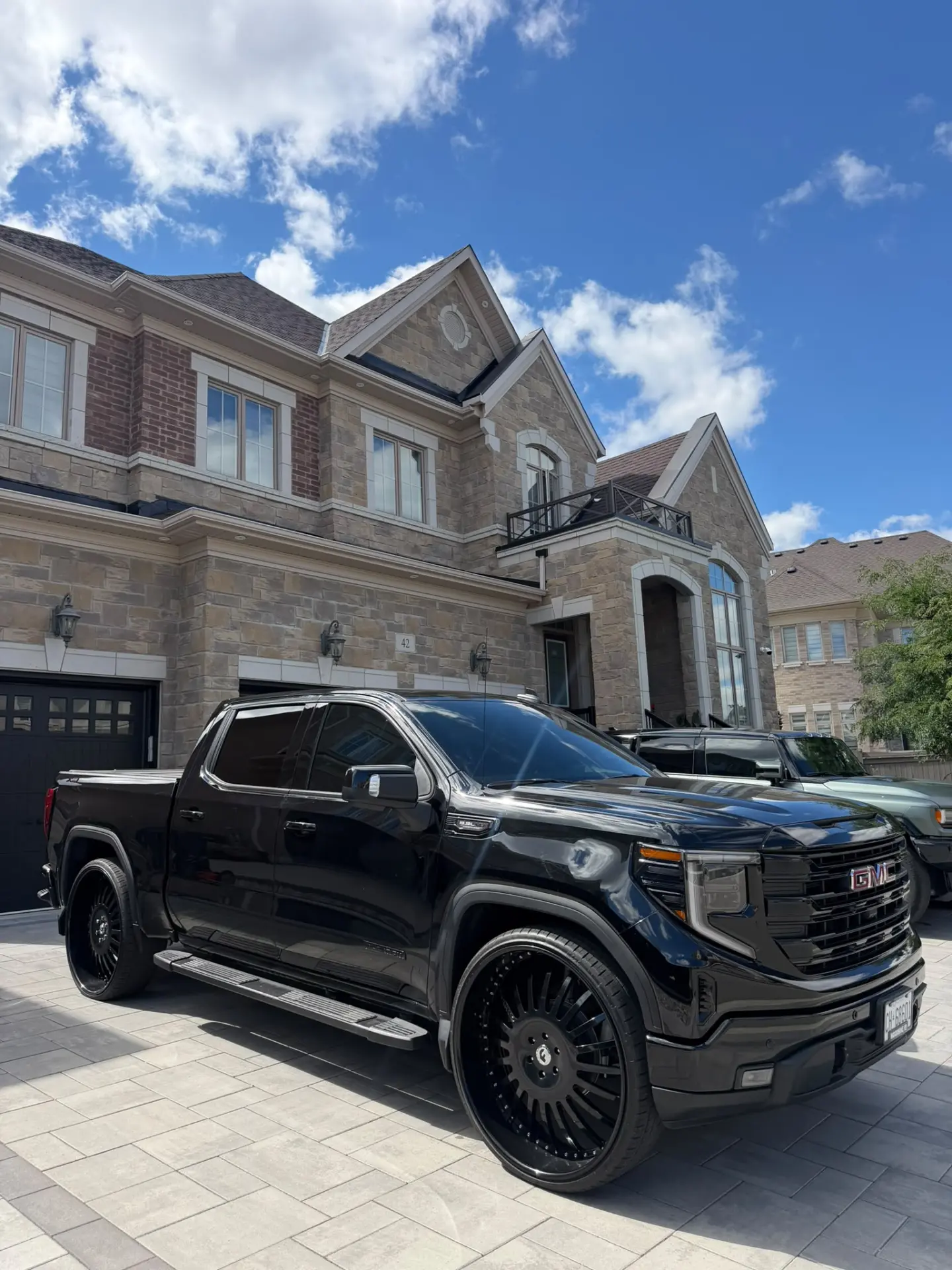 Gloss black GMC Sierra with tinted glass parked on a stone driveway